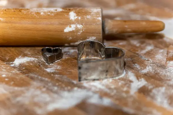 a rolling pin with flour and cookie molds in the kitchen