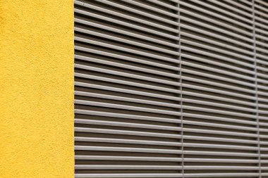 Kapalı panjurlu sarı bir ev duvarı.