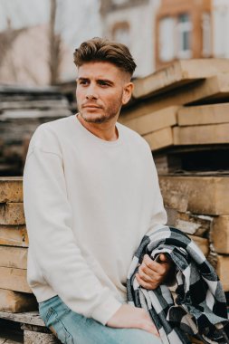 Şehirde beyaz kazaklı çekici bir genç adam.