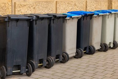 Şehirdeki kaldırımda farklı çöp tenekeleri var.