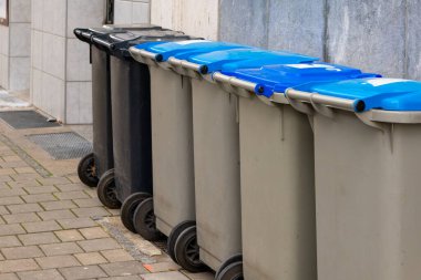 Şehirdeki kaldırımda farklı çöp tenekeleri var.