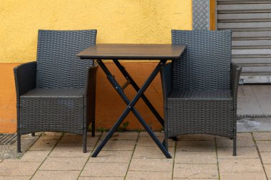 Şehirde turuncu bir duvarın önündeki sandalyeler.