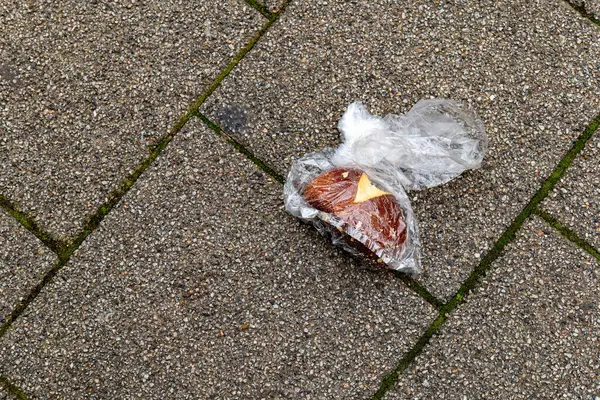an old thrown away bread roll in a plastic bag on the street
