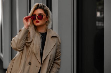 Şehirde siyah gömlekli, güneş gözlüklü, bronz tenli bir kadın var.