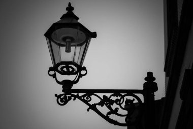 Üzerinde ışık olan lamba direği, siyah beyaz bulutlu gökyüzüne karşı siluetlendi.