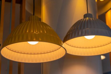 Modern bir iç mekanda seçici bir odak noktasında ampullü sarı ve beyaz asılı lambalar.