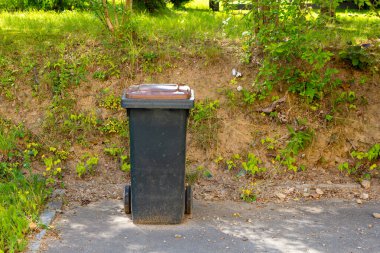 Yolun kenarında bir çöp tenekesi duruyor.
