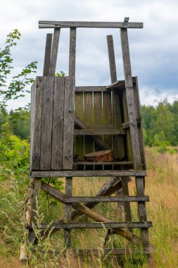 Merdiveni ve bankı olan ahşap bir av binası.