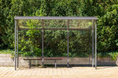 Arka planda bir ağaç ve bank olan bir otobüs durağı.