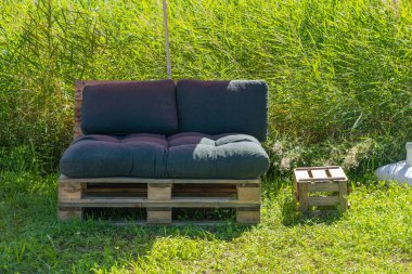 Siyah minderli ahşap bir bank çimenli bir tarlada oturuyor