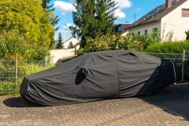 Bir araba siyah bir muşambayla kaplıdır..