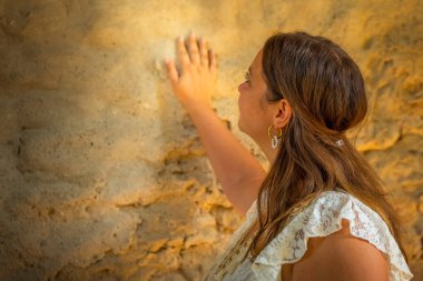 Bir kadın duvarın önünde duruyor ve eliyle ona dokunuyor.