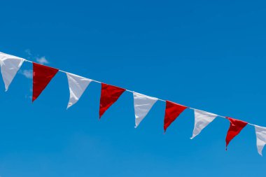 Gökyüzünde kırmızı ve beyaz çizgili uzun bir bayrak çizgisi asılı.