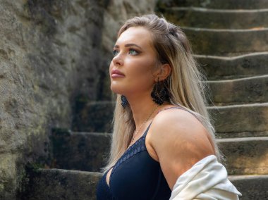 Siyah kolsuz tişörtlü bir kadın merdivenlerde dikiliyor.