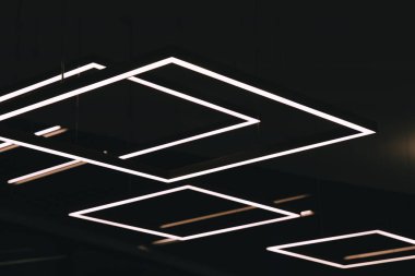 Bir tavana yakın çekim, birden fazla beyaz sıra dikdörtgen ışık, geometrik desen oluşturur.