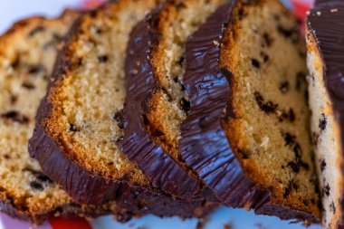 Çikolata kaplı bir somun ekmeğin yakın çekimi. Ekmek dilimlere ayrılır ve beyaz bir tabağın üzerinde oturur. Dilimler çikolatayla kaplıdır, ekmeğe zengin ve hoşgörülü bir görünüm verir.