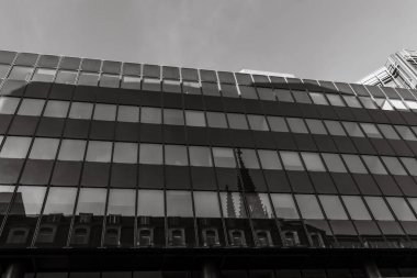 Cam pencereler, şehir merkezinde eski ve yeni mimarinin bir karışımını sergileyen gösterişli ve modern bir binanın ortasındaki gotik bir kulenin çarpıcı yansımasını gösteriyor..