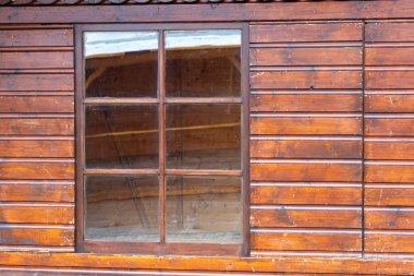 Yıpranmış odunlarla çerçevelenmiş ahşap bir pencere, sakin bir ortamda sıcak bir öğleden sonra ışığı ile aydınlatılan kırsal cazibeyi ve zanaatkarlığı gözler önüne serer..