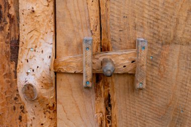 Güzel bir ahşap kapı sürgüsü, rahat bir kulübede kırsal bir kapıyı emniyete alır. Kilit, sanatsal ahşap işçiliğini vurgulayarak, eşsiz ayrıntıları ve dokuları gösterir..