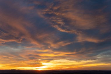 Güneş batarken sıcak renkler gökyüzüne yayıldı ve nefes kesici bir manzara yarattı. Aşağıdaki manzara yumuşak ışıkla yıkanmış, dingin atmosferi güçlendiriyor.