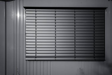 Kapalı panjurlar, sakin bir odada hafif ışığı filtreler, gölgeler bırakır ve sabahın erken saatlerinde sakin bir atmosfer yaratır.