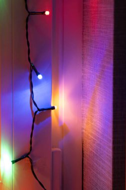 Titreşimli sicim ışıkları duvarda asılı, sıcak kapalı alanda renkli yansımalar yapıyor. Yumuşak parıltı rahatlamak için mükemmel bir ortam yaratır..