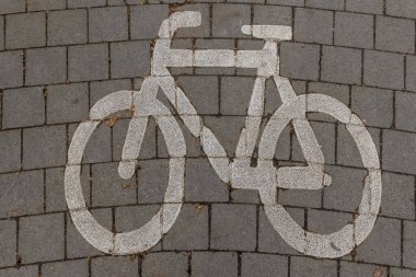 Kaldırıma boyanmış beyaz bisiklet sembolü, sakin bir şehir ortamında gün boyunca kendini adamış bir bisiklet şeridini gösteriyor..