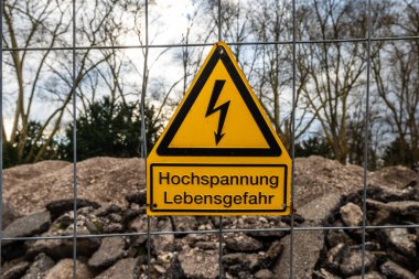 Yüksek voltajı ve hayati tehlikeyi işaret eden parlak sarı bir uyarı işareti. Almanca 'da yüksek voltajın hayati tehlike arz ettiği anlamına geliyor.