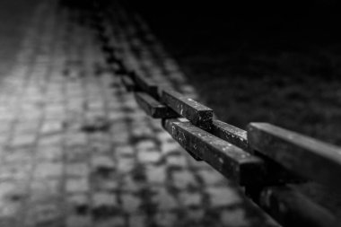 Zincir halkaları kaldırım taşı yolunda kısmen aydınlatılır. Karmaşık gölgeler bırakır. Düşük ışık dokuları vurgular, aydınlık ve karanlık alanlar arasında katı bir zıtlık yaratır..