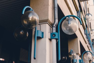 Tarafsız bir bina cephesine karşı mavi sokak aydınlatma donanımları içeren mimari unsurlar şehirde şık bir kentsel atmosfer yaratıyor..