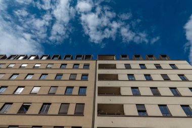 Komşu iki bina, çok sayıda pencere ve balkonun sergilendiği modern bir mimari stil sergiliyor..