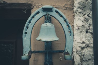 Güneşin yumuşak ışığını yansıtan, yıpranmış bir yapıdan sarkan büyüleyici mavi bir çan. Kırsal duvar bu kırsal bölgenin davetkar atmosferine karakter katıyor..