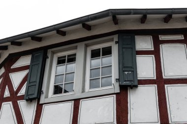 Tuhaf, yarı ahşap bir bina, eşsiz mimarisini gözler önüne sererek uzun duruyor. Yıpranmış kepenkler eski pencereleri çerçeveliyor, bu köyün atmosferindeki zamanın geçişinin bir kanıtı..