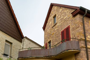 İki komşu binanın arasına yerleştirilmiş bu davetkar taş ev, sakin bir akşamda ahşap bir balkon ve kırmızı aksanlar sergiliyor..