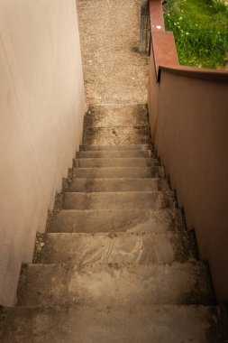 Yıpranmış beton adımlar zarif bir şekilde doğanın güzellikleriyle çevrili verimli bir bahçeye doğru iniyor, ziyaretçileri akşamın yumuşak ışığı altında aşağıdaki dinlendirici alanı keşfetmeye çağırıyor..