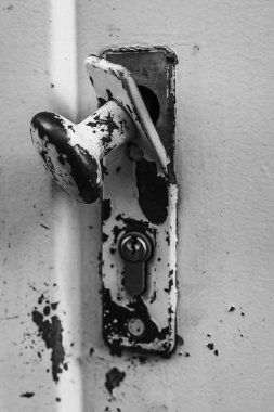 Yakın plan çekimde, kabuk soyulmuş boya ve yaşın sergilendiği bir kapı kolu ve kilidi görülüyor. Bu ayrıntı, geçmişteki bir çağın cazibesini ve hikayelerini yansıtıyor..