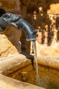 Süslü ejderha şeklindeki bir su birikintisinden kristal berrak bir su birikintisi güzel yapılmış bir havuza dönüşür. Güneş ışığı parıldayan yüzeyde dans eder, taşın etrafındaki dokuları vurgular..