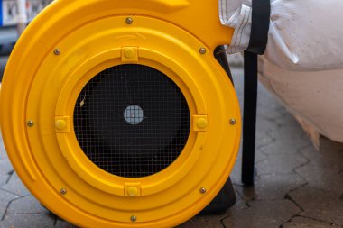 Parlak sarı bir üfleyici belirgin bir şekilde duruyor. İşçiler çeşitli işlerle meşgulken hava kanalları dolanıyor. Toz, etkin bir yenileme ortamı sergileyerek ışıkta yüzüyor..