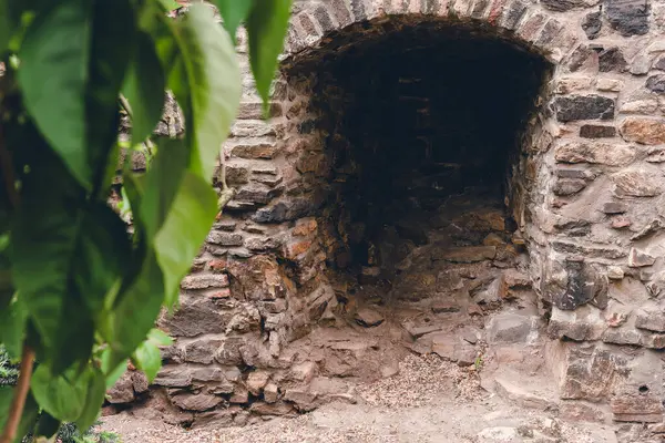 Huzurlu bir an, canlı yeşil yapraklarla kısmen gizlenmiş eski bir taş kemer yolunu yakalar. Giriş, sakin bir tarihsel ortamda keşif yapmaya davet ediyor. Yumuşak güneş ışığıyla yıkanmış..