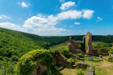 Antik taş kalıntıları sarmaşıklarla kaplanmış, kıvrımlı yeşil tepelerle çevrili. Yumuşak bulutlu huzurlu mavi bir gökyüzü bu zamansız topraklara huzur getirir..