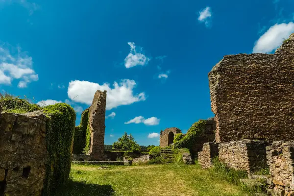 Güneşin sıcaklığında güneşlenen tarihi bir yapının kalıntıları, canlı yeşillik ve geniş mavi gökyüzü ile çevrili. Zaman, bir zamanlar büyük bir yapının kalıntıları arasında duruyor..