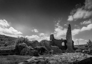 Güneş ışığı, bir zamanların görkemli taş yapısının yıpranmış kalıntılarını çarpıcı bir gökyüzü altında yemyeşil tepelerin arasına yerleştirerek tarihini düşünmeye teşvik eder..