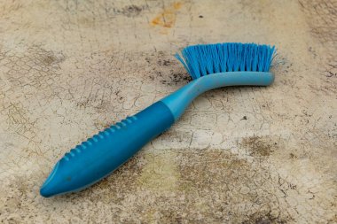 Canlı bir turkuaz temizlik fırçası sessiz, desenli bir yüzeye yerleştirilir, kılları ve ergonomik tasarımı sergilenir. Bu araç eylem için istekli görünüyor, önümüzdeki görevleri düzenleme veya fırçalama ipuçları.