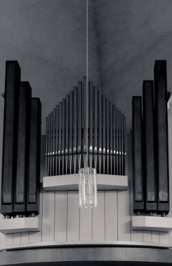 Büyük organ kilisede belirgin bir şekilde duruyor, boruları tavana doğru uzanıyor, sanatsal bir kolye vasıtasıyla yumuşak ışığı yansıtıyor. Huzurlu atmosfer, düşüncelere ve saygıya davet eder..