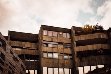 Yenilikçi mimari, geniş pencereli ve canlı balkonlu modern bir konut kompleksinde altın saat boyunca bulutlu bir gökyüzüne karşı sergilendi..
