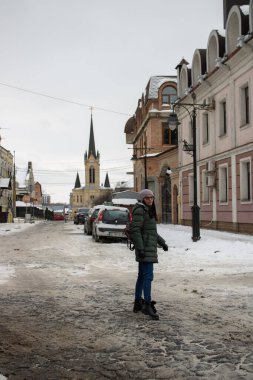 Eski ortaçağ kasabası Lutsk Ukrayna 'da yürüyen bir kadın. Mimari şehir taşları caddesi ve tarih binalarına kış manzarası. Karda milli dönüm noktası. Turistlerin ünlü eğlencesi.