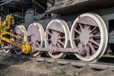Buharlı lokomotife yakın çekiş tekerlekleri ve çubuklar. Eski trenin süspansiyonunun eski bir parçası. Nadir demiryolu taşımacılığını detaylandırır - kol ve şasi, dingil ve bağlantı. Parça Parçası.