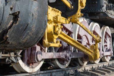 Buharlı lokomotife yakın çekiş tekerlekleri ve çubuklar. Eski trenin süspansiyonunun eski bir parçası. Nadir demiryolu taşımacılığını detaylandırır - kol ve şasi, dingil ve bağlantı. Parça Parçası.