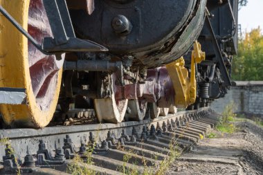Buharlı lokomotife yakın çekiş tekerlekleri ve çubuklar. Eski trenin süspansiyonunun eski bir parçası. Nadir demiryolu taşımacılığını detaylandırır - kol ve şasi, dingil ve bağlantı. Parça Parçası.