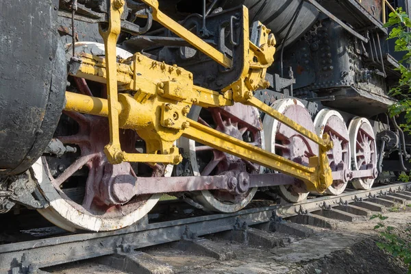 Buharlı lokomotife yakın çekiş tekerlekleri ve çubuklar. Eski trenin süspansiyonunun eski bir parçası. Nadir demiryolu taşımacılığını detaylandırır - kol ve şasi, dingil ve bağlantı. Parça Parçası.
